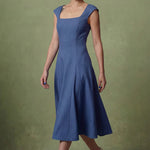 A professional woman modeling an elegant mid-blue midi dress featuring a classic square neckline, cap sleeves, and a flattering A-line flare skirt, perfect for both business and social occasions.