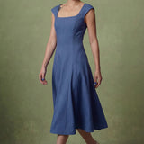 A professional woman modeling an elegant mid-blue midi dress featuring a classic square neckline, cap sleeves, and a flattering A-line flare skirt, perfect for both business and social occasions.