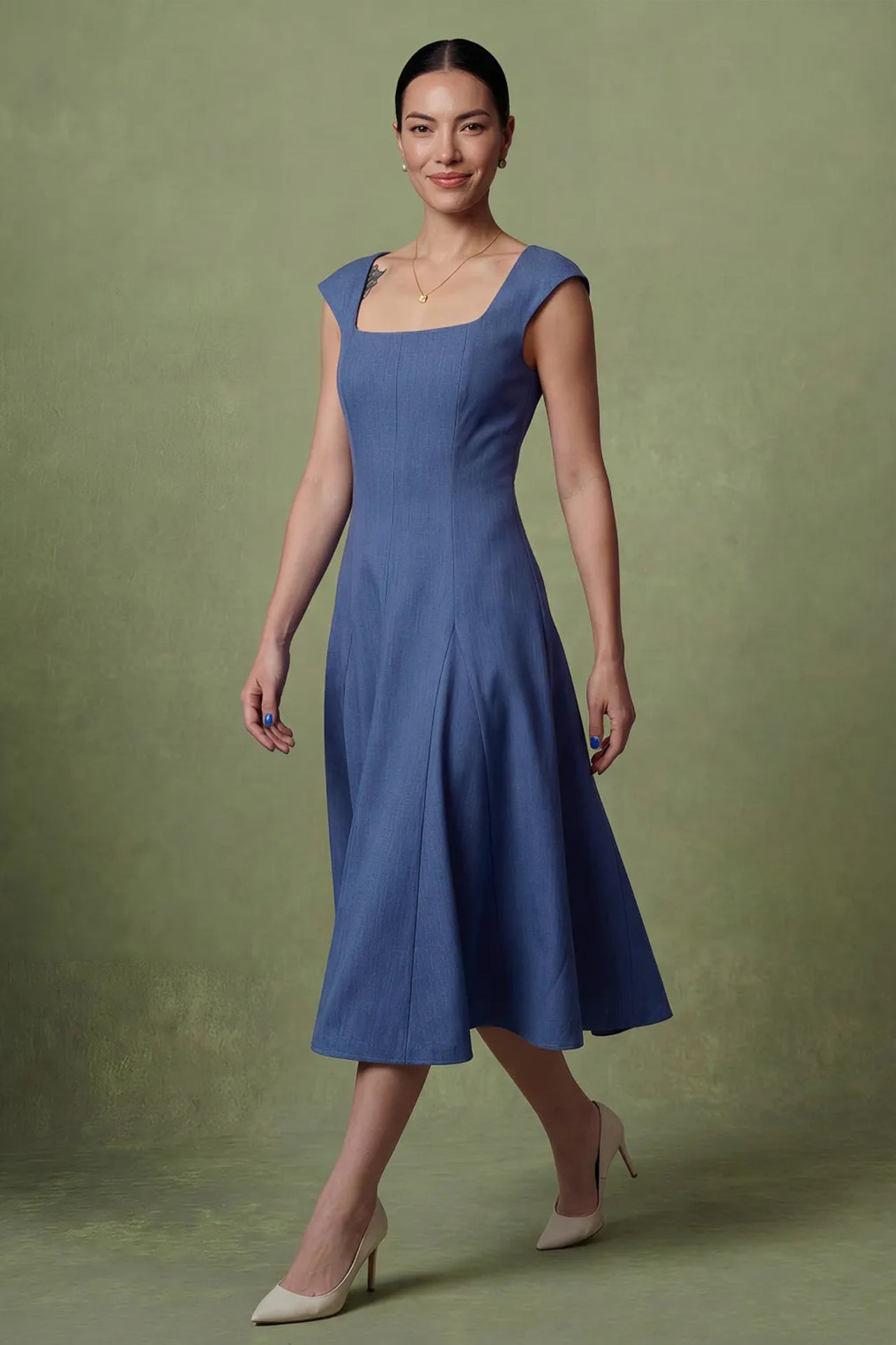 A professional woman modeling an elegant mid-blue midi dress featuring a classic square neckline, cap sleeves, and a flattering A-line flare skirt, perfect for both business and social occasions.