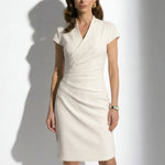 Two professional models wearing elegant sleeveless surplice V-neck sheath dresses in soft mint green and cream ivory, featuring sophisticated side ruched detailing and a tailored slim fit for a polished office look.