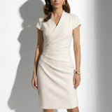 Two professional models wearing elegant sleeveless surplice V-neck sheath dresses in soft mint green and cream ivory, featuring sophisticated side ruched detailing and a tailored slim fit for a polished office look.
