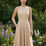 Two professional models wearing elegant halter-neck pleated maxi dresses in khaki and mustard yellow, featuring a high-waist A-line silhouette and side pockets, perfect for a sophisticated summer vacation or garden party look.