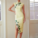 A professional woman wearing a stunning pale yellow sleeveless dress, featuring a traditional mandarin collar, exquisite white floral embroidery appliques along the neckline and hem, and an elegant side slit for a sophisticated modern oriental look.