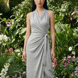 Two professional models wearing elegant halter-neck wrap maxi dresses in heather grey and vibrant sky blue, featuring a sophisticated draped V-neckline and waist tie for a minimalist summer or resort look.