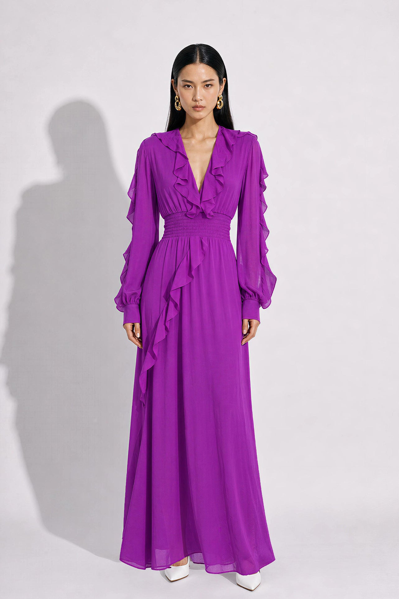A style comparison of two elegant long-sleeve chiffon maxi dresses; the left showcasing a vibrant purple dress with a deep V-neckline and tiered ruffles along the sleeves, and the right featuring a sophisticated grey version styled with a matching neck scarf and smocked waistband.