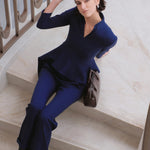 A style comparison of three women wearing tailored two-piece power suits featuring long-sleeve split V-neck jackets with dramatic asymmetrical peplum hems and matching cuffed wide-leg trousers; shown in vibrant crimson red, deep navy blue, and pale ice blue.