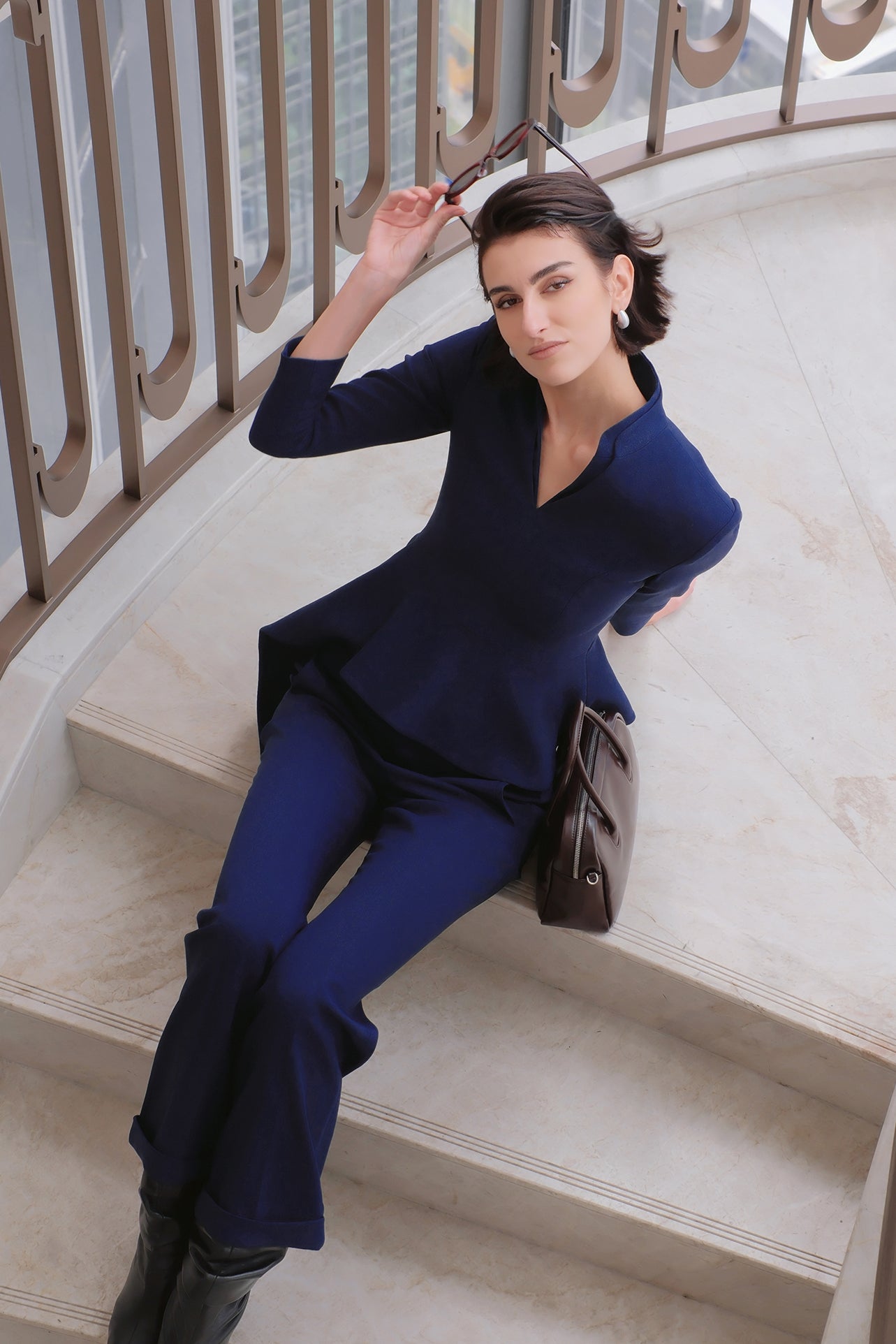 A comparison of three professional women modeling tailored power trouser suits featuring architectural split V-neck jackets with dramatic asymmetrical peplum hems and matching wide-leg trousers in crimson red, deep royal navy, and ice blue.