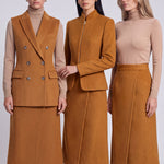 An elegant Asian woman posing in a luxurious camel wool two-piece suit featuring a sleeveless double-breasted longline vest cinched with a wide black belt, paired with a matching midi column skirt and black opera gloves.