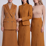 An elegant Asian woman posing in a luxurious camel wool two-piece suit featuring a sleeveless double-breasted longline vest cinched with a wide black belt, paired with a matching midi column skirt and black opera gloves.