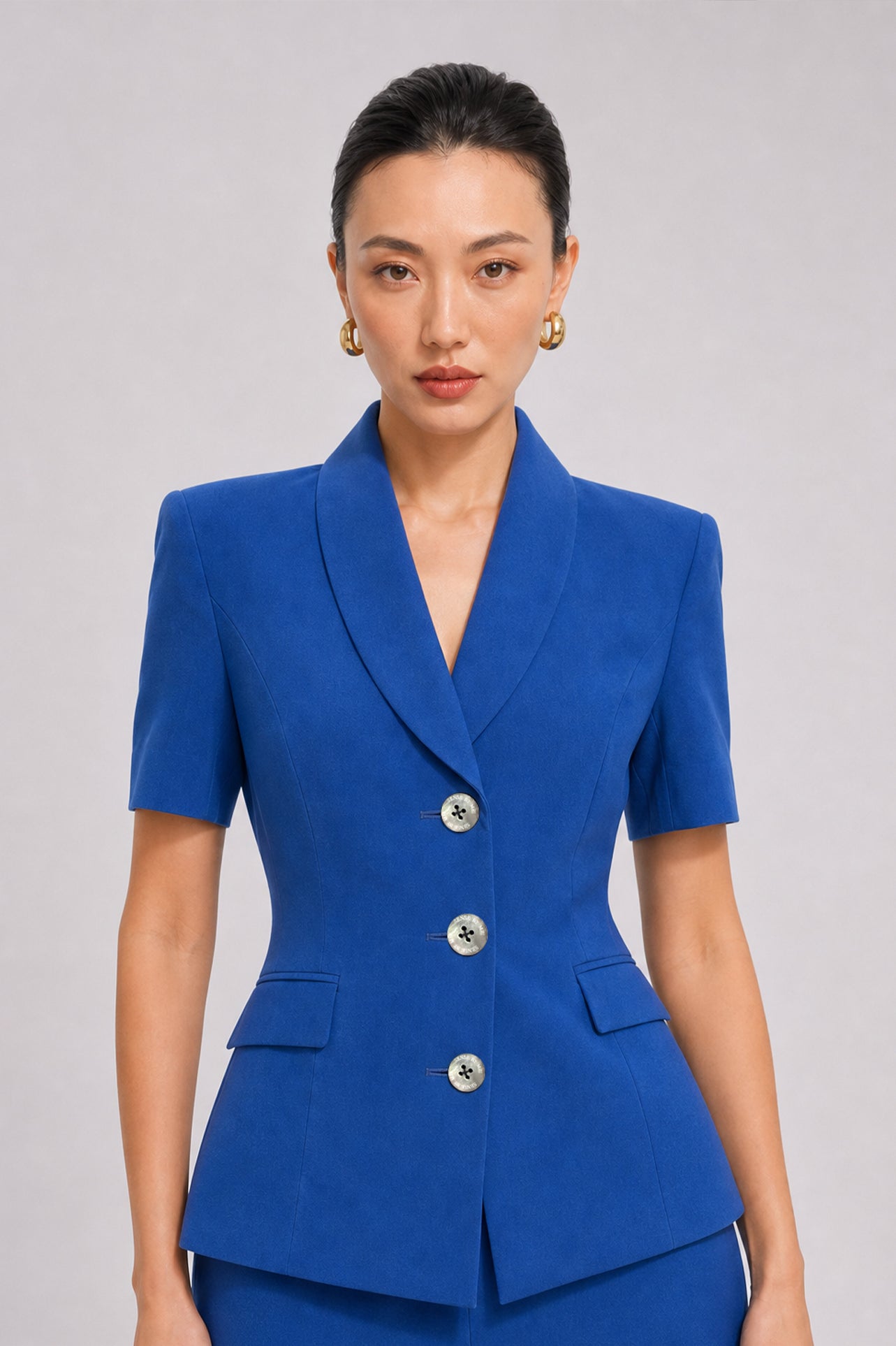 A style comparison of two professional summer short-sleeve blazers featuring an elegant shawl collar, three-button front, and flap pockets; the left shown in vibrant royal blue and the right in sophisticated light beige.