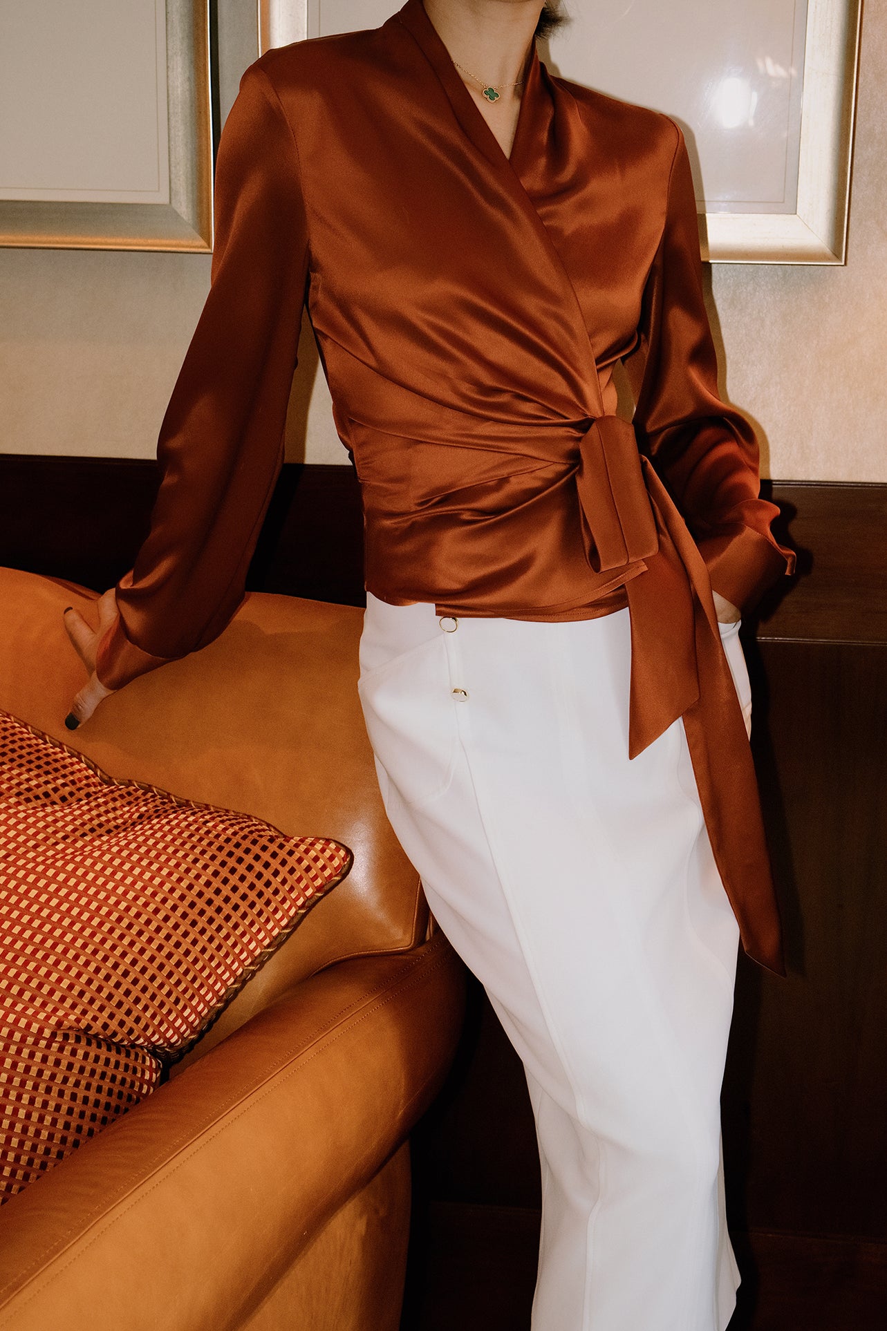 A professional woman wearing a high-end white silk wrap blouse with a side-tie detail, paired with a tailored black high-waisted pencil skirt for a sophisticated executive office look.