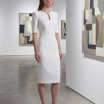 A sophisticated professional woman wearing a tailored black longline blazer with a belted waist and gold buckle, featuring a slimming executive silhouette for a formal office look.