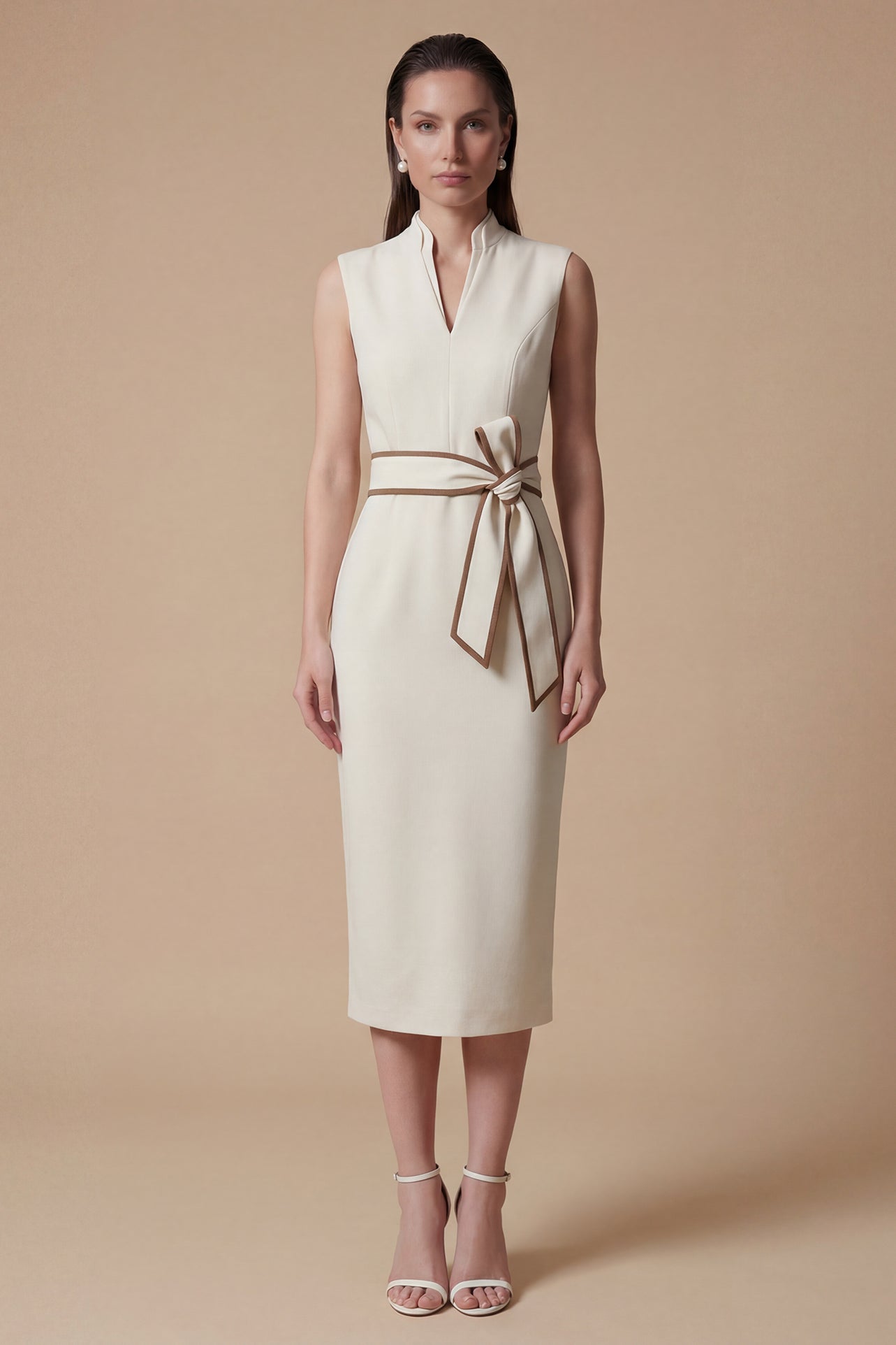 A professional woman modeling an elegant white sleeveless midi dress, featuring a sophisticated stand collar with a V-neck slit and a chic brown contrast bow belt for a polished office look.
