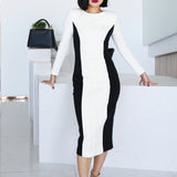 A professional woman wearing a sophisticated black and white color-block midi dress, featuring slimming side panels, long sleeves, and an elegant black belt with a gold buckle for a modern executive office look.