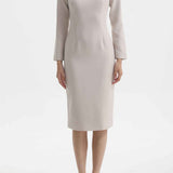 A professional woman wearing a sophisticated black long-sleeve midi dress, featuring a unique notched square neckline and a tailored slim-fit pencil silhouette for a polished executive office look.