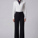 A professional woman wearing sophisticated black high-waisted straight-leg trousers, featuring a tailored silhouette with creased front details for a polished executive office look.