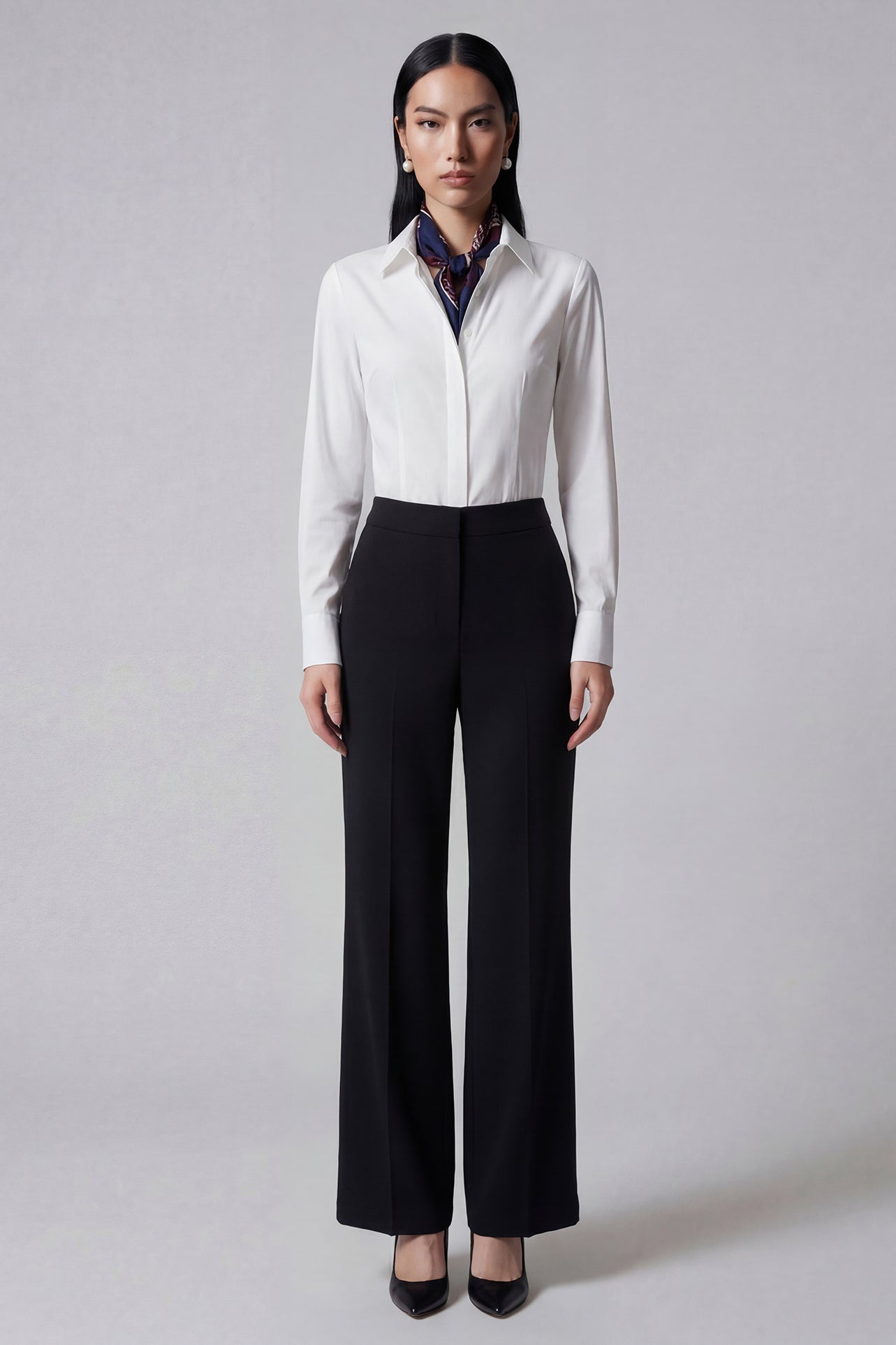 A professional woman wearing sophisticated black high-waisted straight-leg trousers, featuring a tailored silhouette with creased front details for a polished executive office look.