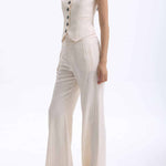 A professional woman wearing sophisticated cream pinstripe high-waisted wide-leg trousers, featuring a tailored loose-fit silhouette and styled with a pearl handbag for an elegant old money office look.