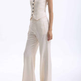 A professional woman wearing sophisticated cream pinstripe high-waisted wide-leg trousers, featuring a tailored loose-fit silhouette and styled with a pearl handbag for an elegant old money office look.