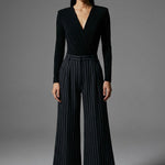A professional woman wearing sophisticated high-waisted wide-leg pinstripe trousers in charcoal black, featuring a tailored slimming fit for a powerful executive office look.