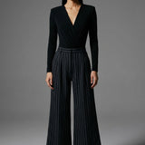 A professional woman wearing sophisticated high-waisted wide-leg pinstripe trousers in charcoal black, featuring a tailored slimming fit for a powerful executive office look.