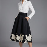 A professional woman wearing a classic crisp white long-sleeve slim-fit blouse with a sharp point collar, styled with a navy blue pencil skirt for a polished executive office look.