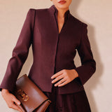 A professional Asian woman wearing glasses and an elegant deep burgundy tailored blazer featuring a sophisticated stand collar with a split V-neckline, structured shoulders, and a clean minimalist front.