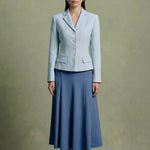 A professional woman modeling a sophisticated light blue tailored blazer with white buttons, perfectly paired with a contrasting navy blue pleated midi skirt for a refined business look.