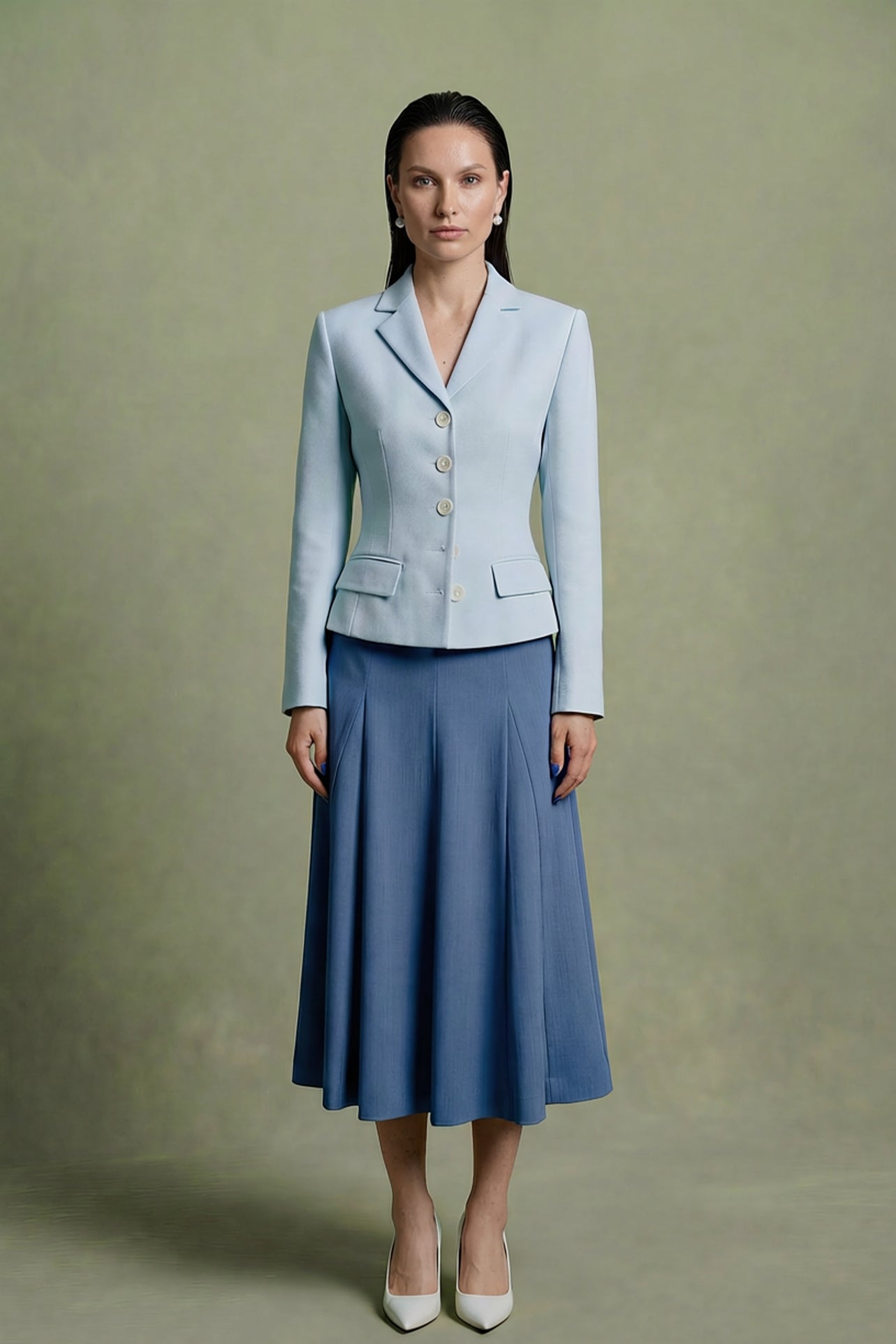 A professional woman modeling a sophisticated light blue tailored blazer with white buttons, perfectly paired with a contrasting navy blue pleated midi skirt for a refined business look.