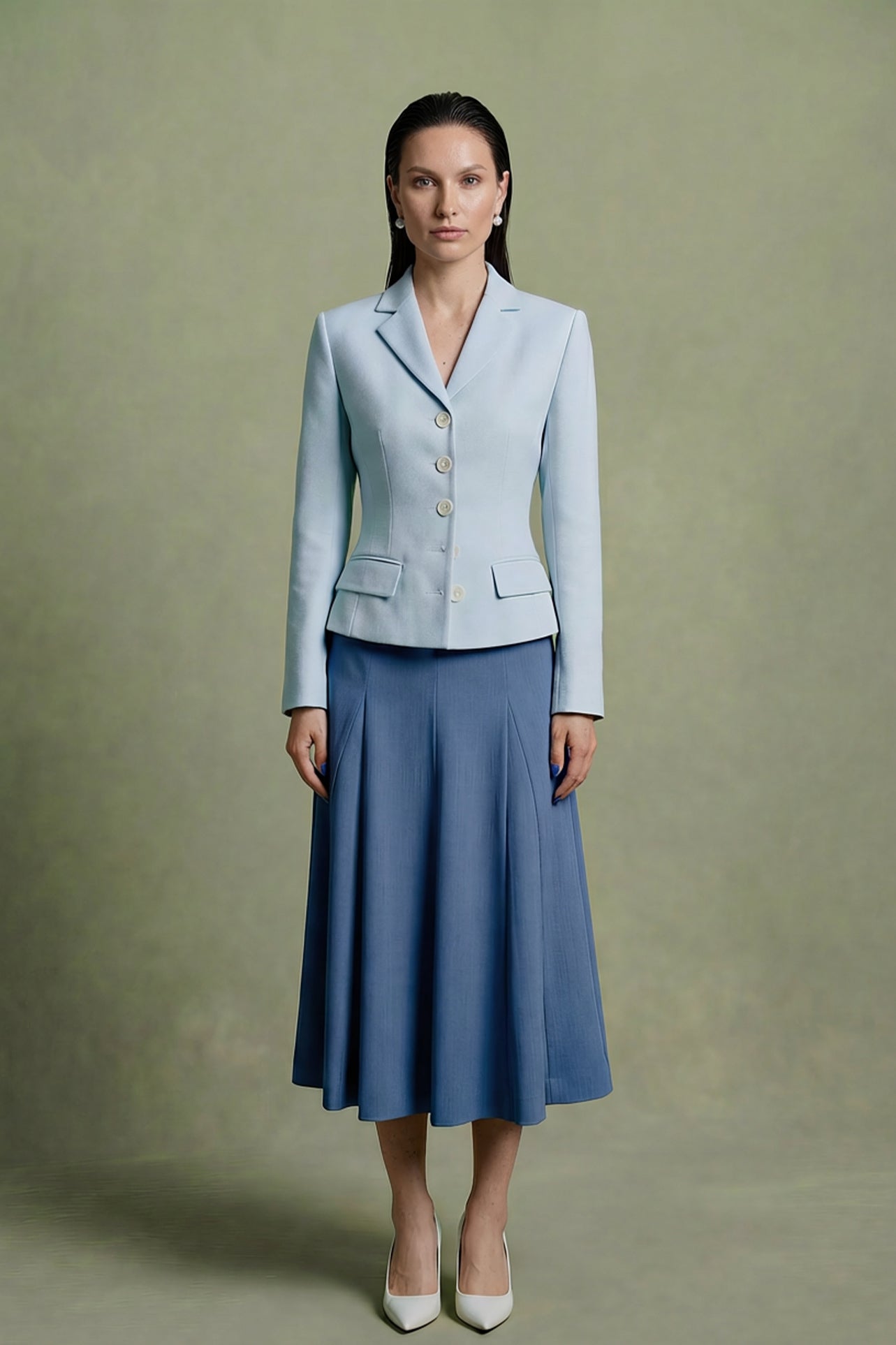 A professional woman modeling a sophisticated light blue tailored blazer with white buttons, perfectly paired with a contrasting navy blue pleated midi skirt for a refined business look.