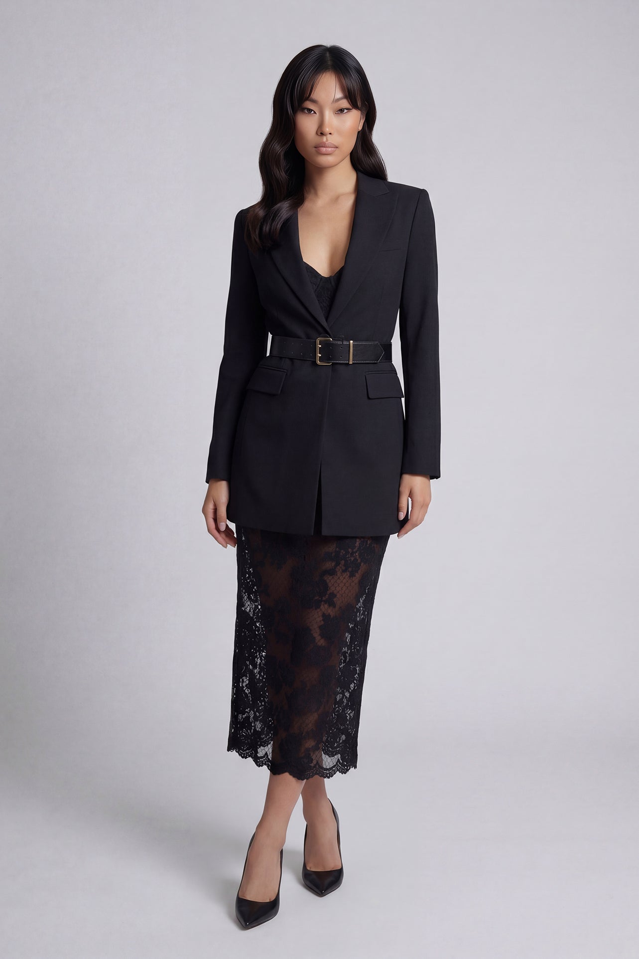 A professional woman wearing a sophisticated black belted blazer dress, featuring a tailored slim-fit silhouette with a waist-defining belt for a powerful executive business look.