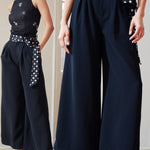 A professional woman wearing sophisticated black high-waisted wide-leg trousers, featuring a flattering high-rise fit and a flowing full-length silhouette for an elegant office look.