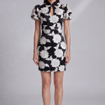 A professional woman wearing a modern black mini qipao dress, featuring elegant white floral embroidery, voluminous puff sleeves, and a chic keyhole neckline with a mandarin collar for a stylish party look.