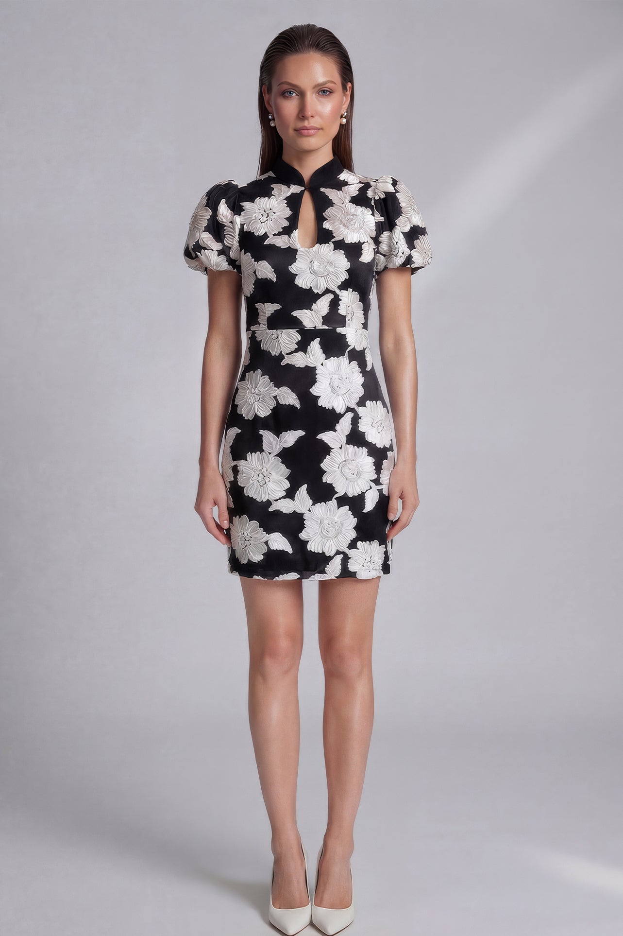 A professional woman wearing a modern black mini qipao dress, featuring elegant white floral embroidery, voluminous puff sleeves, and a chic keyhole neckline with a mandarin collar for a stylish party look.