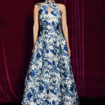 A stunning modern oriental gala dress featuring a classic blue and white porcelain floral print, an elegant halter neck with keyhole detail, and a voluminous A-line full skirt for a sophisticated formal look.
