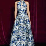 A stunning modern oriental gala dress featuring a classic blue and white porcelain floral print, an elegant halter neck with keyhole detail, and a voluminous A-line full skirt for a sophisticated formal look.