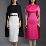 Two professional women wearing sophisticated cape-style dresses: one in a classic black and white monochrome with a thin belt, and the other in a vibrant magenta pink, perfect for a powerful and elegant evening look.