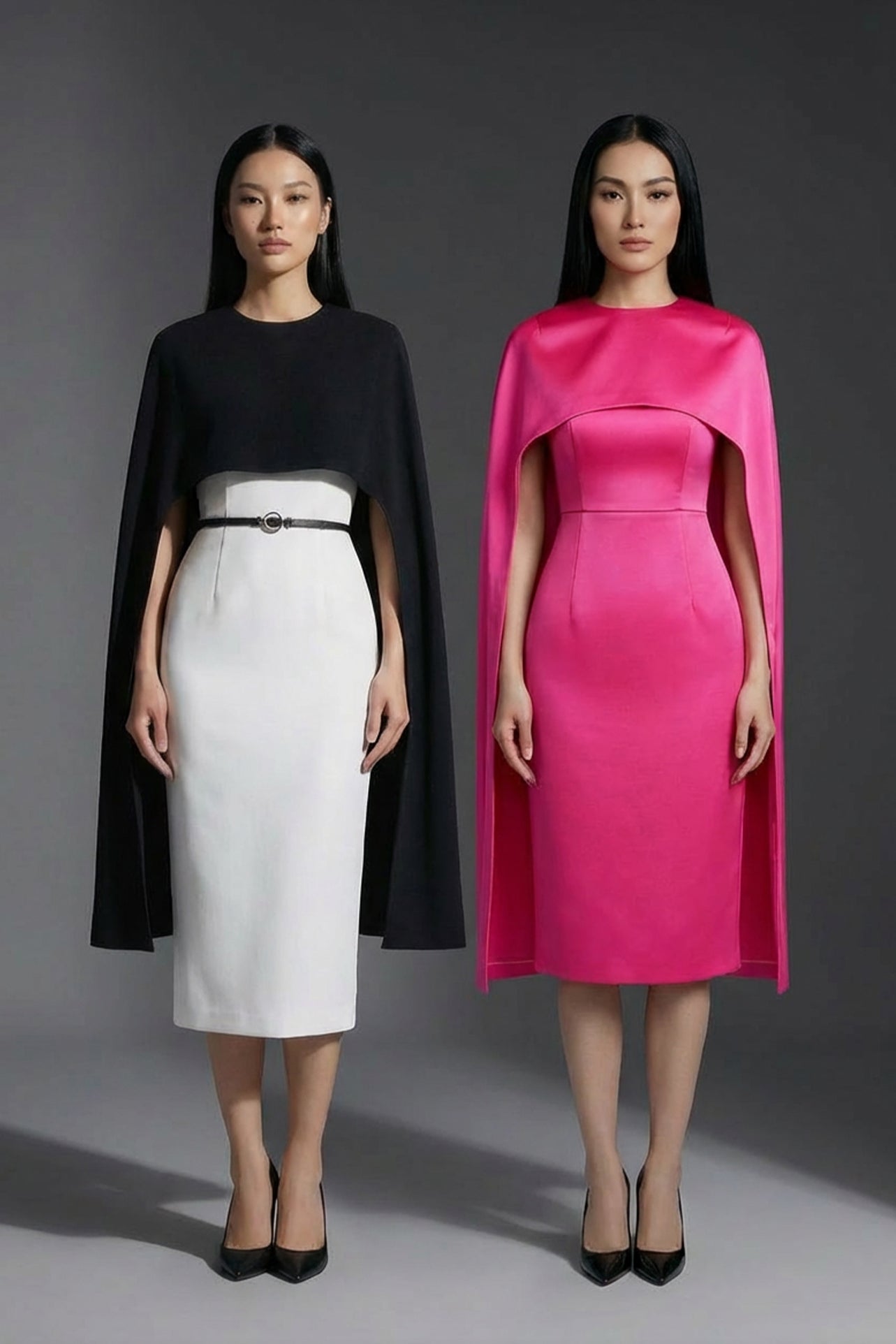 Two professional women wearing sophisticated cape-style dresses: one in a classic black and white monochrome with a thin belt, and the other in a vibrant magenta pink, perfect for a powerful and elegant evening look.