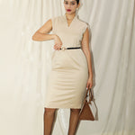 A professional woman wearing a sophisticated beige sleeveless sheath dress, featuring an elegant mandarin collar with a V-neckline and a slim black belt for a polished executive office look.
