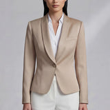 A professional woman modeling a luxurious champagne satin blazer featuring a soft shawl lapel and a single-button closure, elegantly paired with high-waisted white trousers for a sophisticated quiet luxury look.