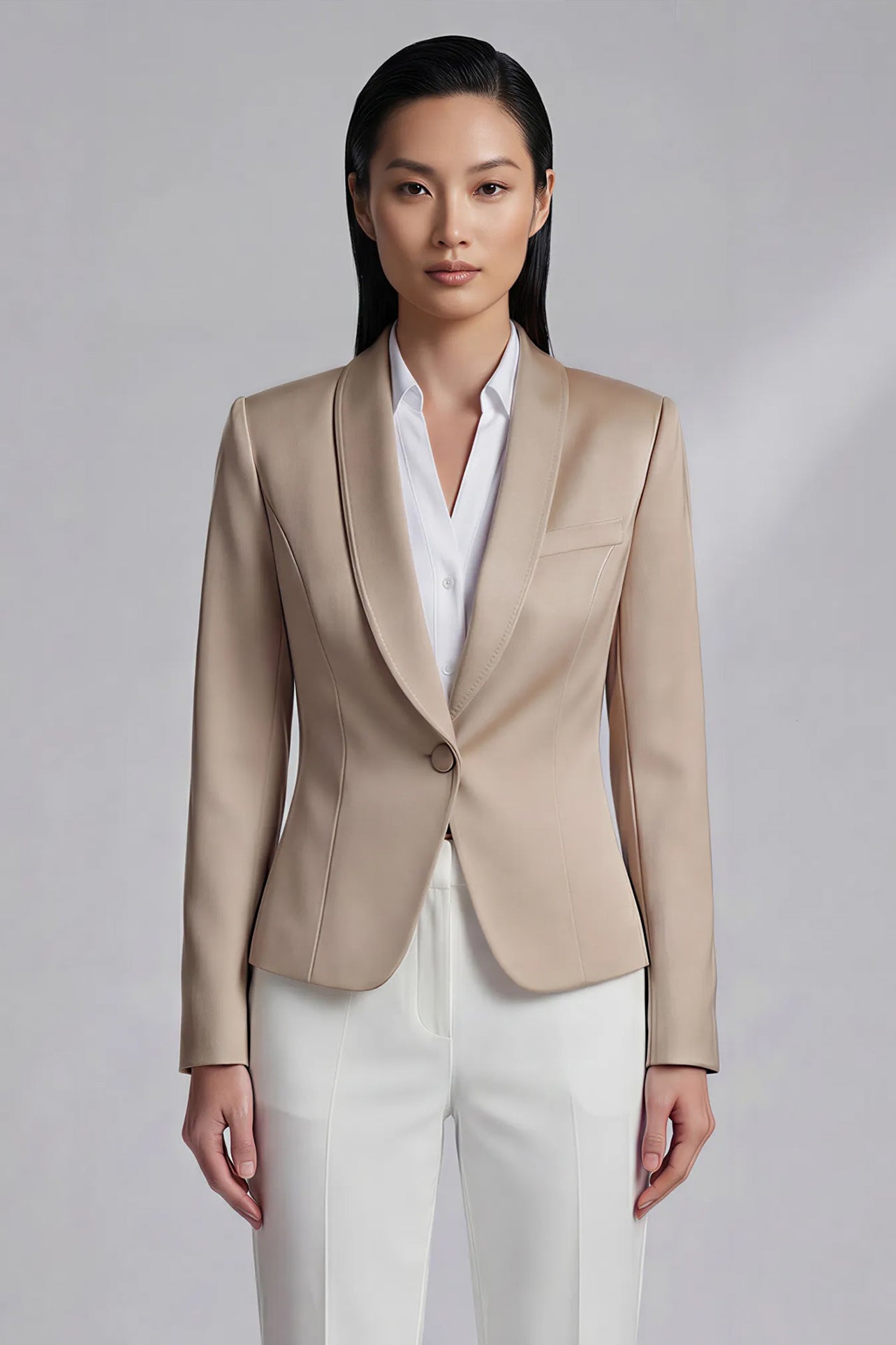 A professional woman modeling a luxurious champagne satin blazer featuring a soft shawl lapel and a single-button closure, elegantly paired with high-waisted white trousers for a sophisticated quiet luxury look.