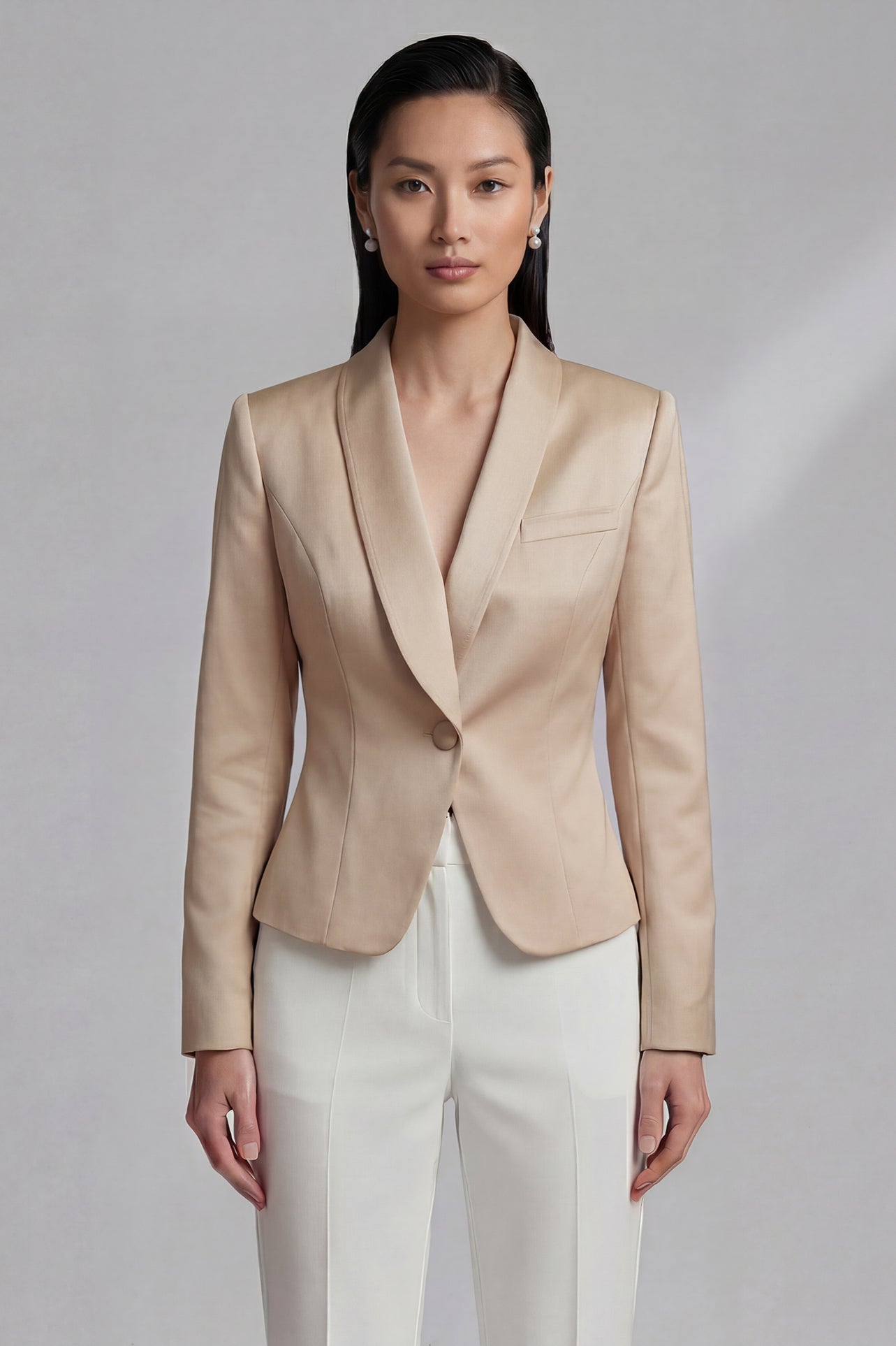 A professional woman wearing an elegant champagne-colored satin blazer with a sophisticated shawl collar and tailored waist, styled for a luxury business or evening event.