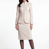 A professional woman wearing a sophisticated beige modern Qipao-inspired skirt suit, featuring a tailored blazer with traditional Chinese frog buttons and a stand collar for an elegant executive office look.