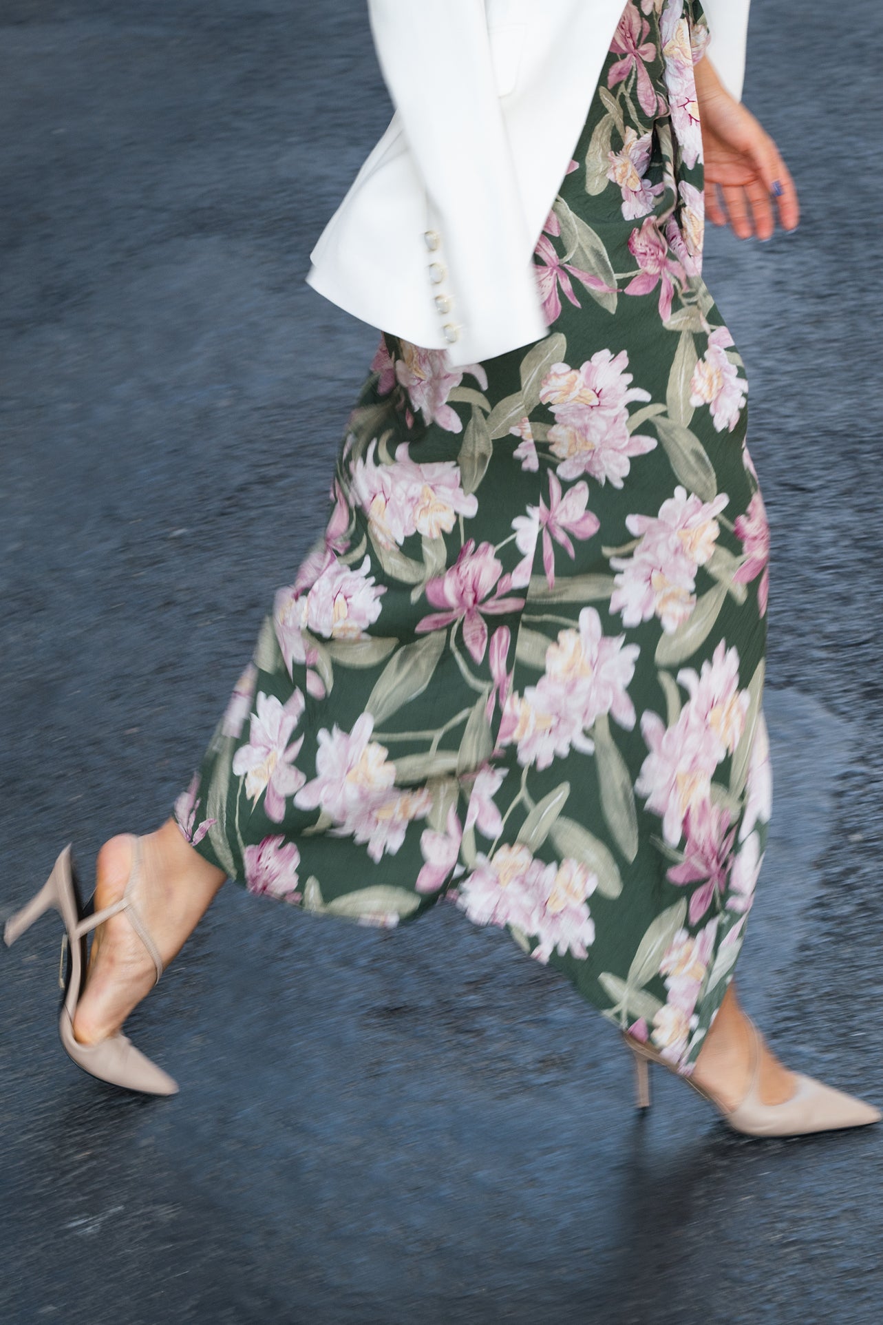 A professional woman wearing a sophisticated dark green wrap dress with a vibrant pink floral print, featuring long sleeves and a slimming waist-tie for an elegant spring look.