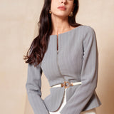 A professional woman wearing a sophisticated grey pinstripe zip-up blazer, featuring a thin white belt with a gold buckle and a tailored slim fit for a modern office look.