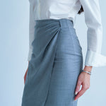 A professional woman wearing a sophisticated grey pencil skirt, featuring an elegant tulip hem and flattering side ruched detailing for a polished office look.
