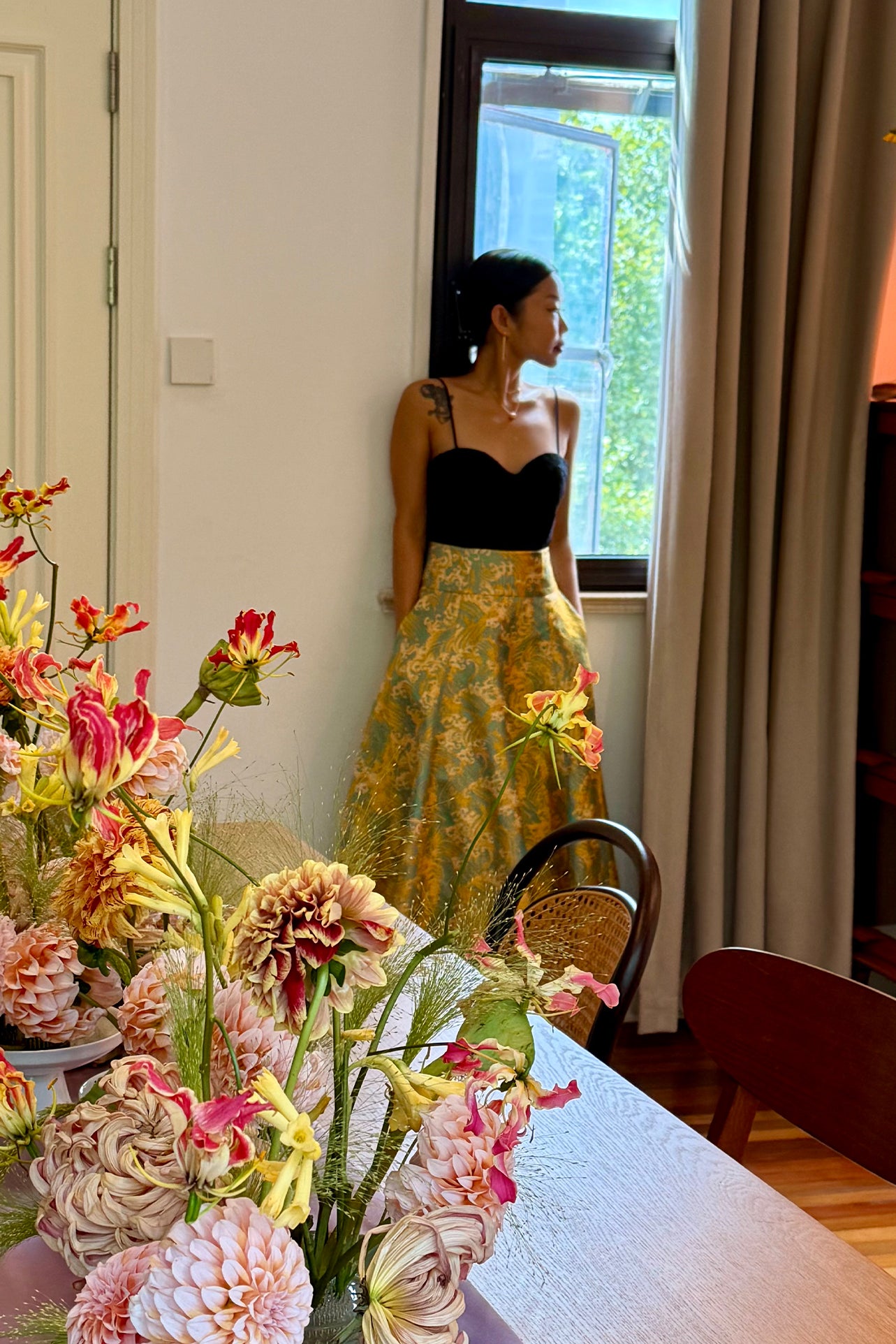 A professional woman wearing a sophisticated high-waisted A-line skirt, featuring a luxurious gold and teal wave pattern jacquard fabric and elegant full-skirt volume for a formal event.