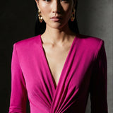 A sophisticated woman wearing a vibrant magenta long-sleeve dress, featuring a plunging V-neckline and an elegant knot-front twist at the waist for a stunning evening gala look.