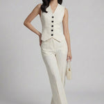 A professional woman wearing sophisticated cream pinstripe high-waisted wide-leg trousers, featuring a tailored loose-fit silhouette and styled with a pearl handbag for an elegant old money office look.