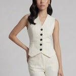 A professional woman wearing a sophisticated off-white pinstripe vest top, featuring a slim-fit tailored silhouette, classic V-neck, and contrasting black buttons for a modern business casual look.